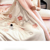 A light pink embroidered quilt with a sheer pink cover draped over a model, showcasing soft fabric texture.