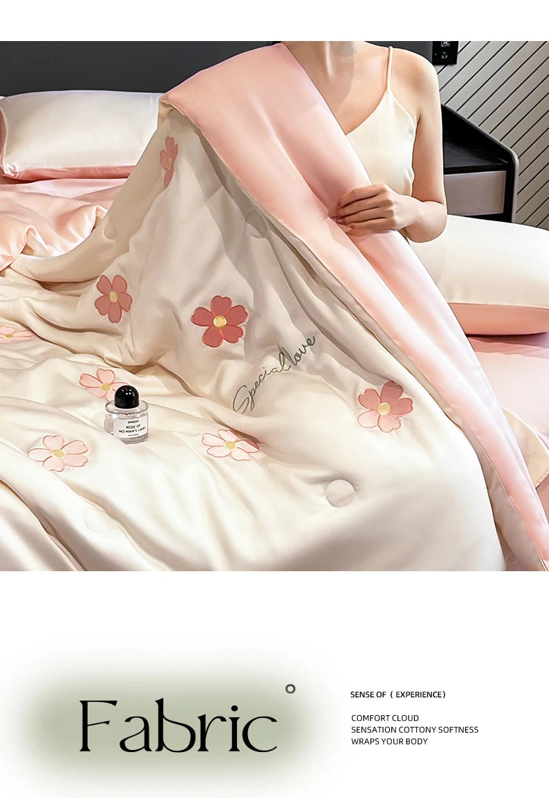 A light pink embroidered quilt with a sheer pink cover draped over a model, showcasing soft fabric texture.