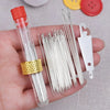 A hand holds a clear tube containing a stainless steel embroidery and knitting needle set with a gold ring and a white plasti