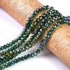 A strand of dark green faceted rondelle glass beads is draped over a natural cork or wood cylinder.