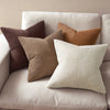 A set of four neutral corduroy throw pillow covers with a patchwork design arranged on a light-colored sofa.