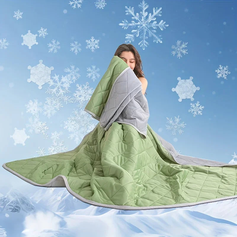 A woman is wrapped in a light green quilted blanket against a snowy blue background.
