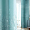 Light blue curtains featuring a white botanical design, shown next to sheer white curtains and a wooden floor.