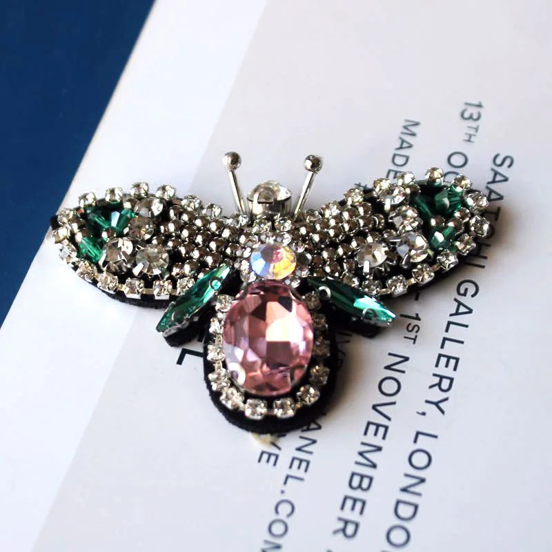 Handmade bee beaded sew-on patches featuring sparkling silver and pink stones on a black fabric background