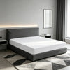 A modern bedroom featuring a bed with a gray headboard and white bedding, illuminated by a strip light, placed on a rug.