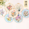 A collection of round embroidery kits featuring various floral patterns and botanical designs on light fabric.
