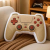 A beige gamer controller plush toy resting on a brown knitted fabric.