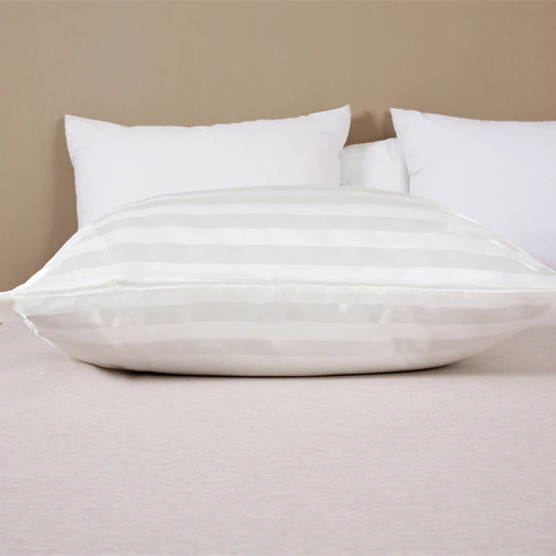 White and light striped pillow covers resting on a beige surface with white pillows in the background.