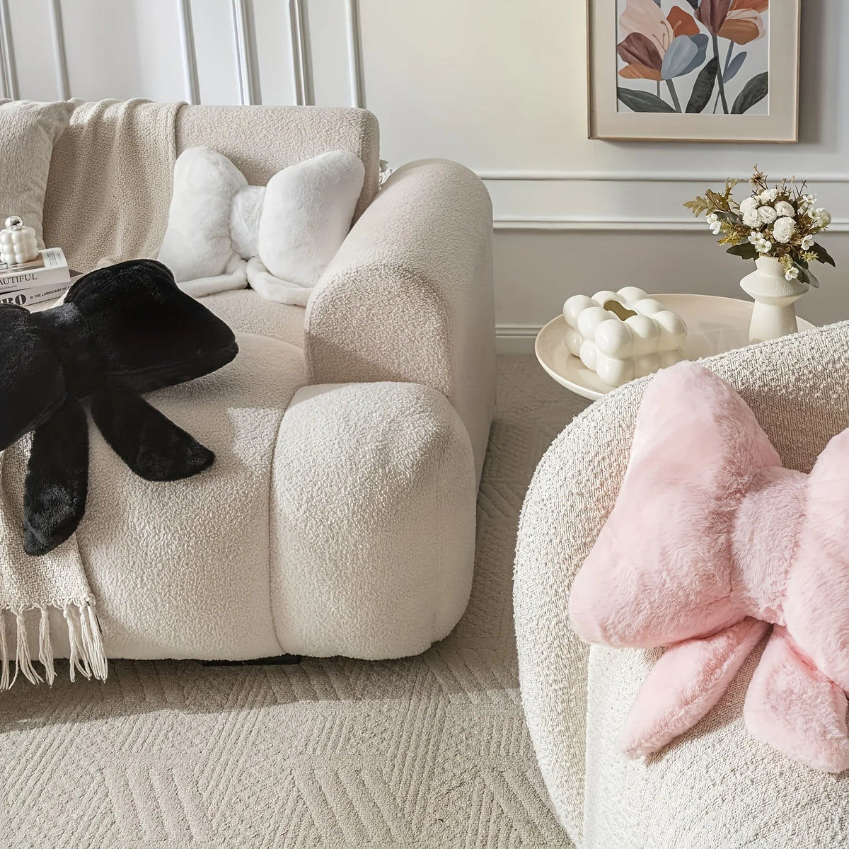 A close-up of a fluffy pink decorative bow pillow resting on a cream upholstered sofa.