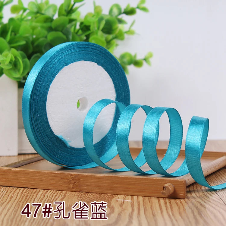 Roll of satin ribbon in various shades of blue and teal on a wooden board