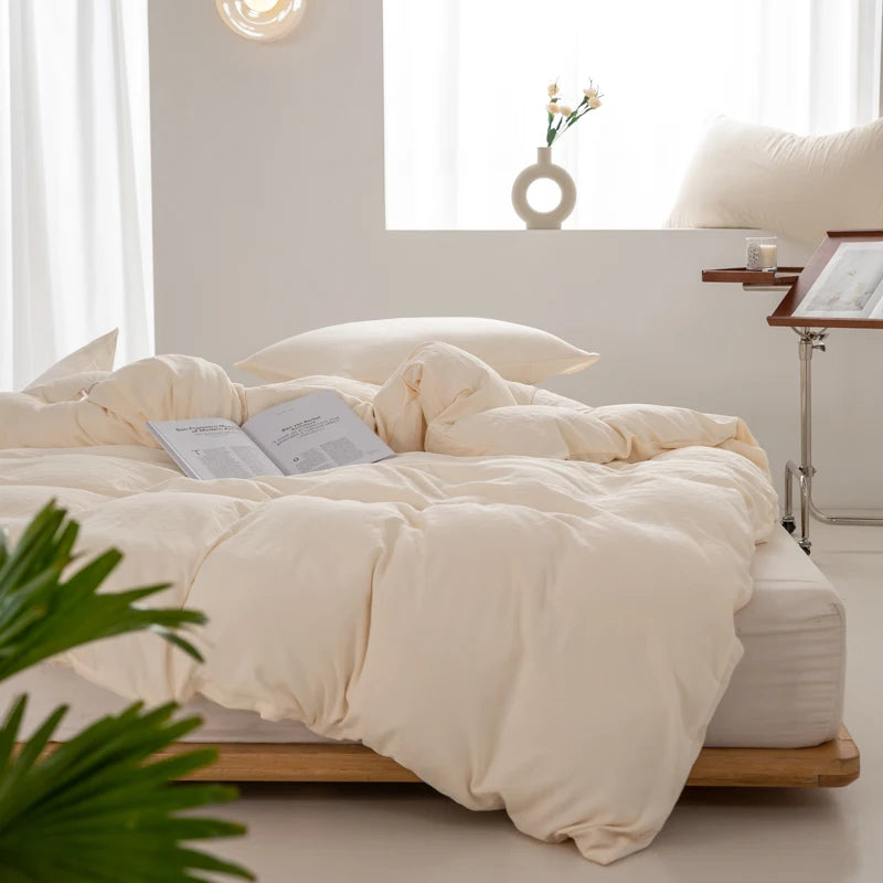 A beige minimalist duvet cover is displayed on a bed with white bedding and natural light.