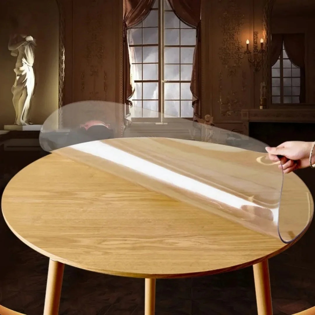 A round waterproof PVC tablecloth with a decorative print is displayed on a wooden table.