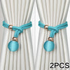 Two pairs of turquoise fabric tiebacks with gold accents shown against a white curtain background