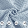 A close-up of a soft, light blue waffle knit blanket folded in a swirl.