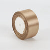 A roll of satin ribbon in a champagne gold color for crafts and gift wrapping.
