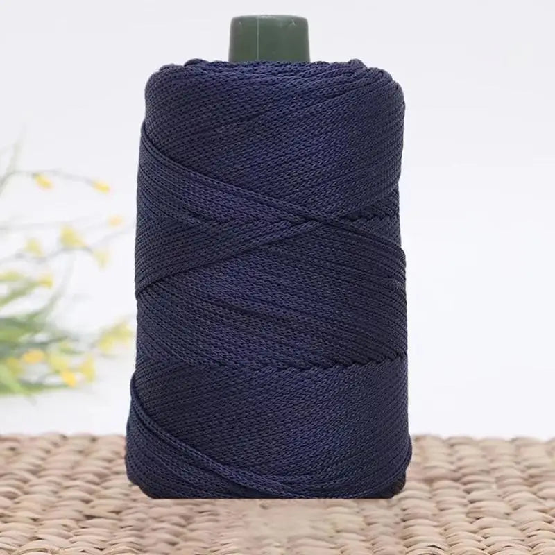 A spool of dark navy blue 3mm ice rope crochet yarn for crafting, resting on a woven mat.