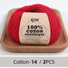 A ball of red organic cotton yarn labeled QJH 100% COTON ORGANIQUE resting on a wooden tray.