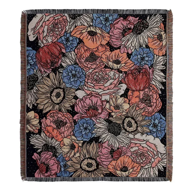 A dark throw blanket featuring a floral and geometric pattern in shades of pink, orange, blue, and cream.
