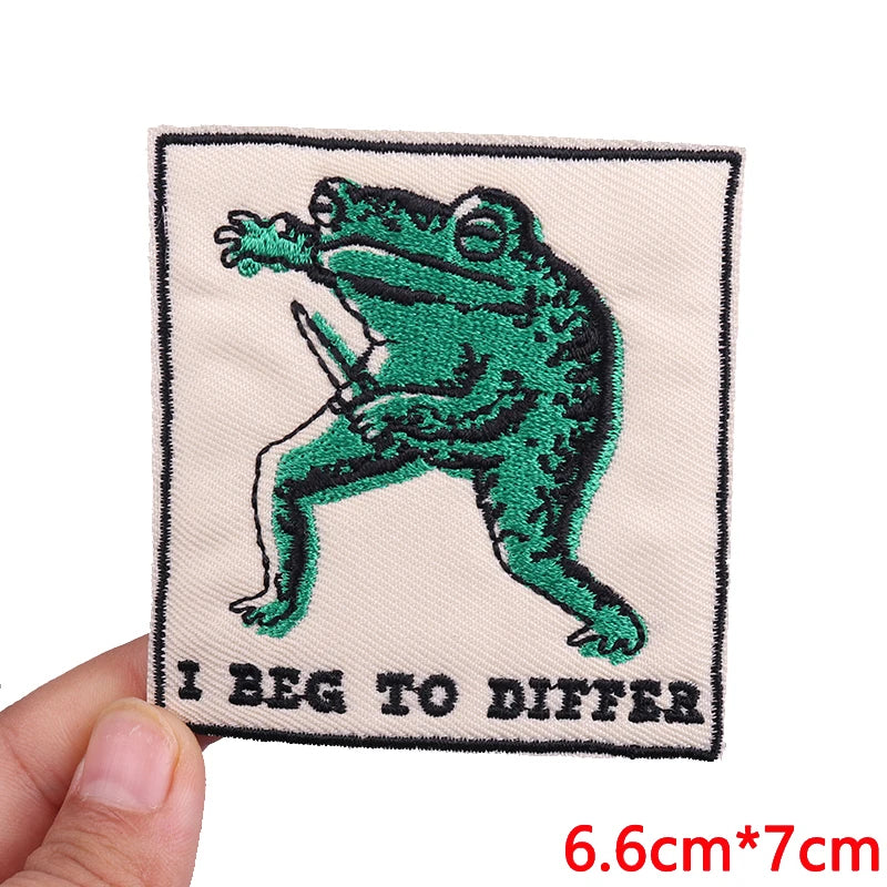 An embroidered patch featuring a green frog with text that reads I BEG TO DIFFER