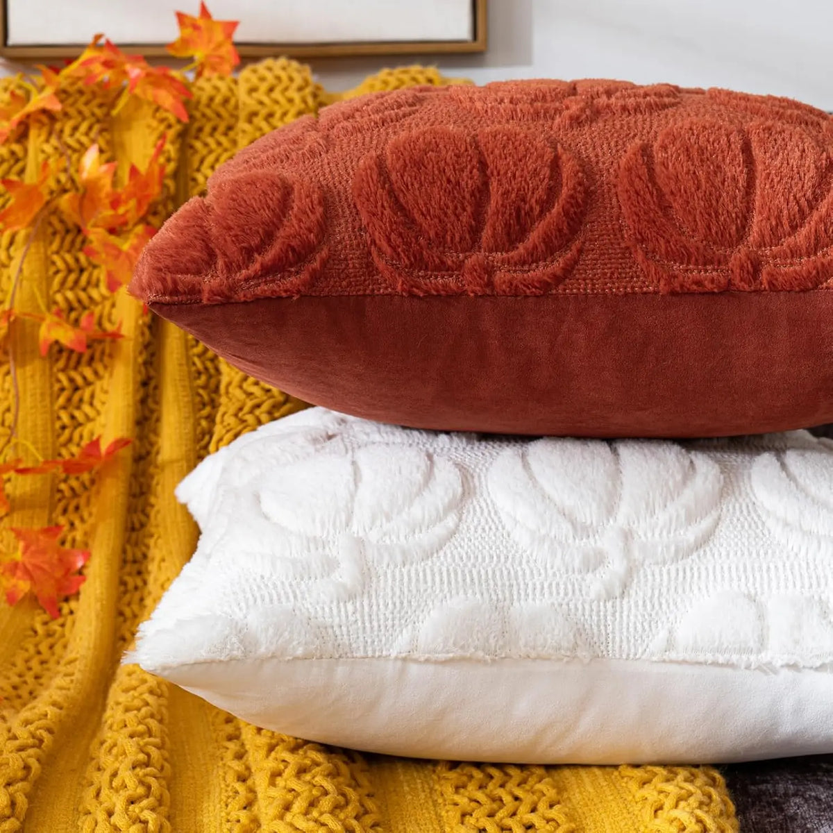 A terracotta colored chenille throw pillow resting on a yellow knitted blanket.