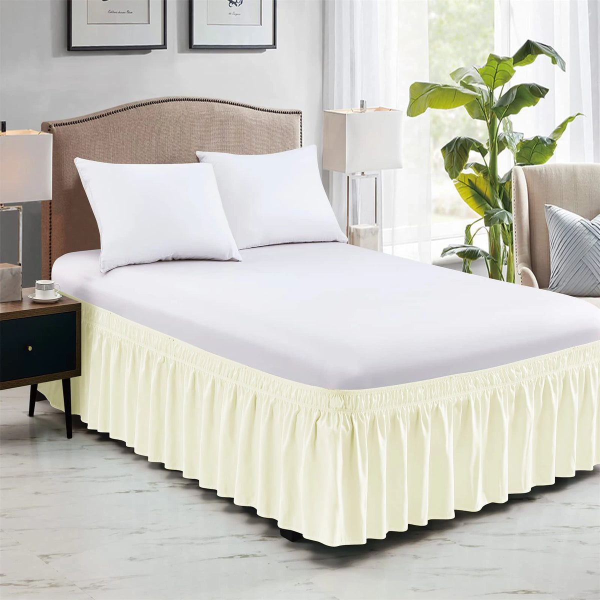 A white bed with a yellow ruffled skirt and white linens in a bedroom setting.