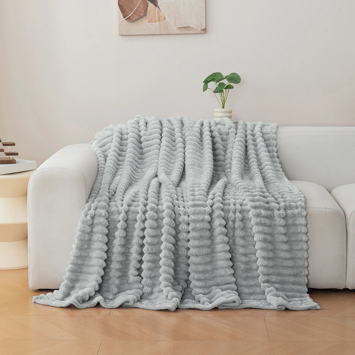 A light gray soft flannel throw blanket draped over a white sofa.