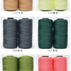 A collection of spools of hand knitting and crochet cord in various colors including beige, yellow, gray, green, and pink.