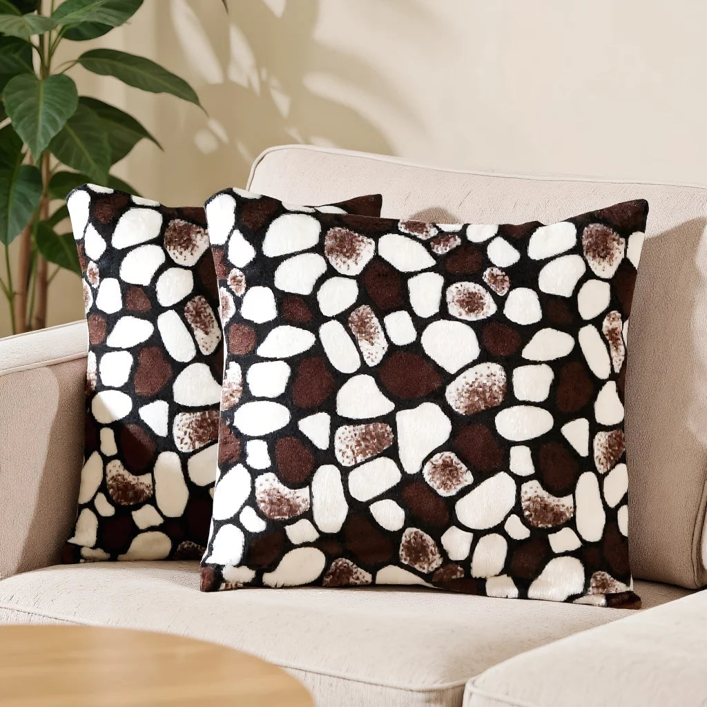 A set of two throw pillows with a brown and white leopard print pattern resting on a light-colored sofa.