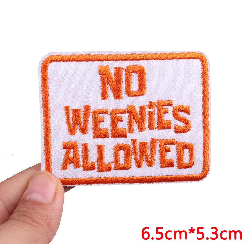 An embroidered patch with the text NO WEENIES ALLOWED in orange thread on a white background.