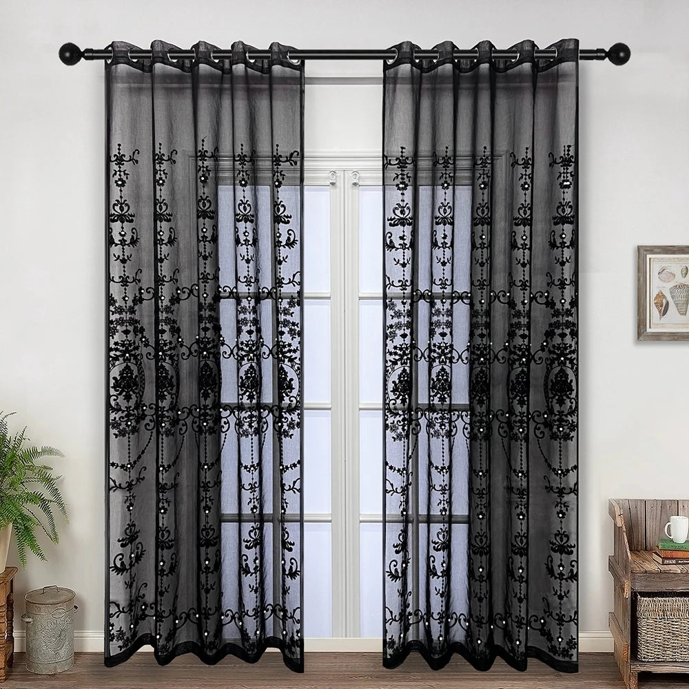 Black sheer curtain featuring pearl and lace embroidery hanging in a doorway.