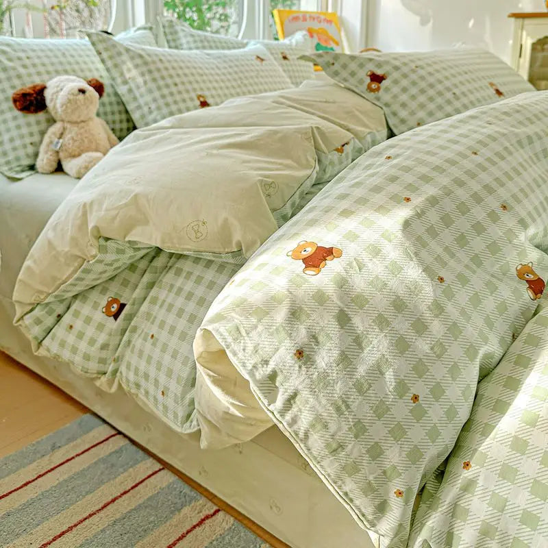 A light green and white gingham duvet and pillow set with small orange accents on a bed.