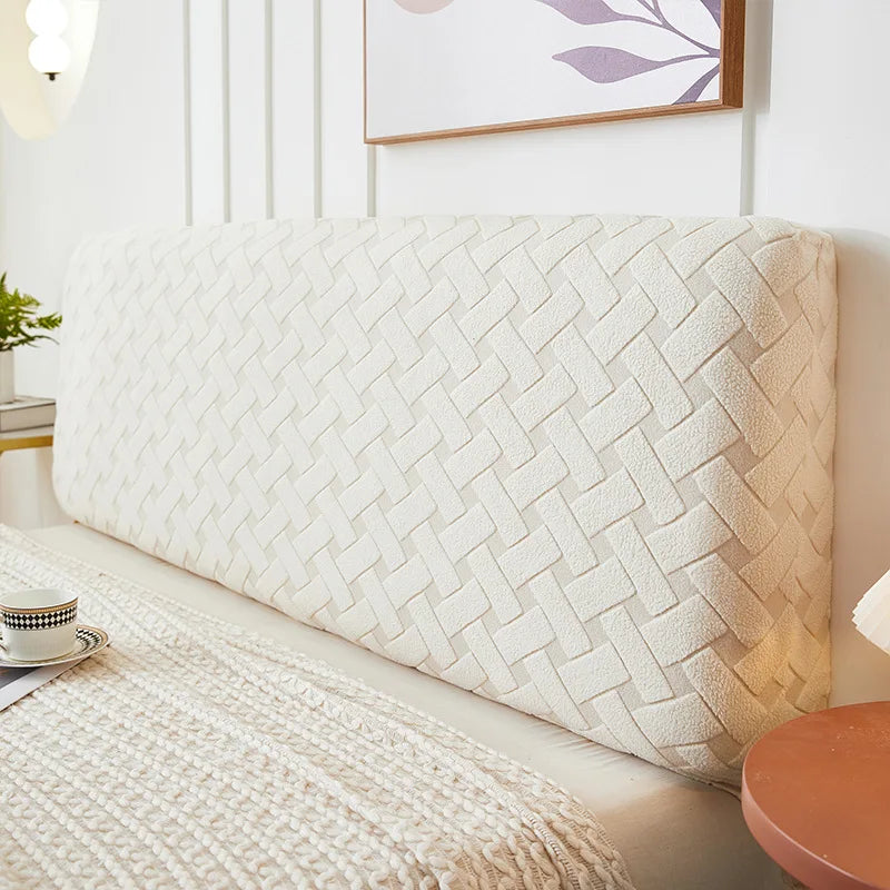 A cream quilted headboard cover is shown against a white wall, resting on a light-colored sofa.