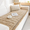 A beige quilted flannel sofa pad cover placed on a white sofa with natural light.
