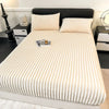 A close-up of thick, cream-colored winter fitted bed sheets on a bed with a black headboard.