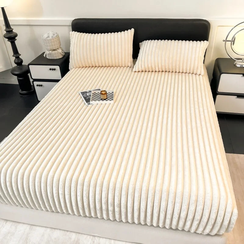 A close-up of thick, cream-colored winter fitted bed sheets on a bed with a black headboard.