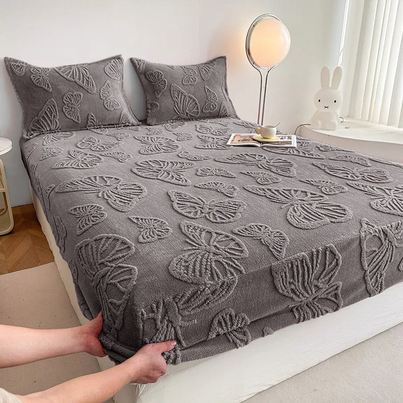 A gray jacquard weave fitted sheet bedding set on a bed with a white headboard and natural light.