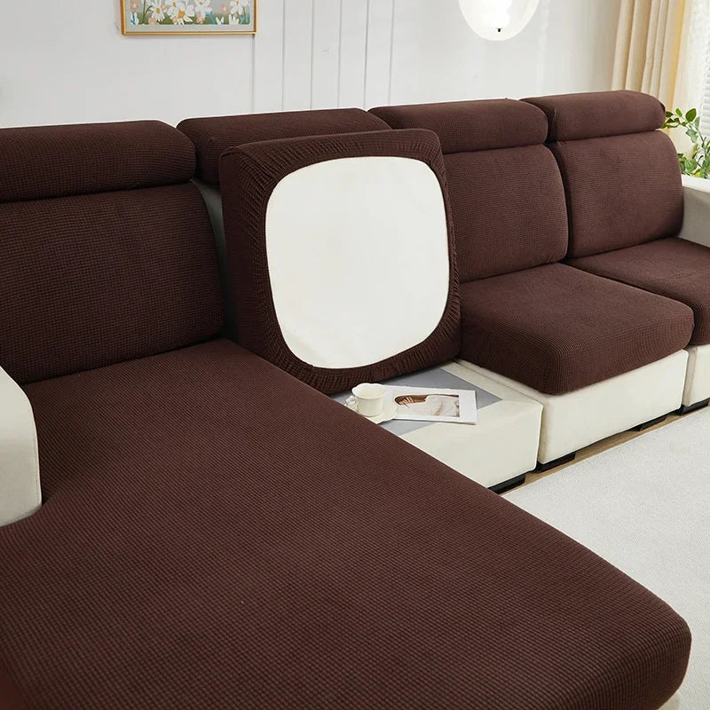 A deep brown jacquard elastic sofa cushion slipcover with a white accent panel shown in a modern living room setting.