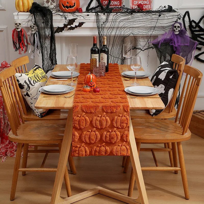 A wooden dining table set for Halloween with an orange fabric runner, pumpkins, and spooky decorations.