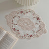 Elegant oval lace embroidered coaster set with pink floral details on a white background