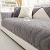 A gray textured sofa cushion cover with a white pillow and a white cup resting on it.