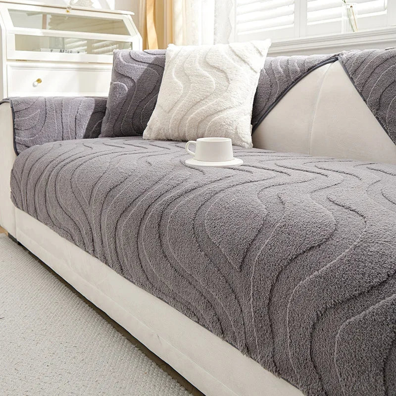 A gray textured sofa cushion cover with a white pillow and a white cup resting on it.