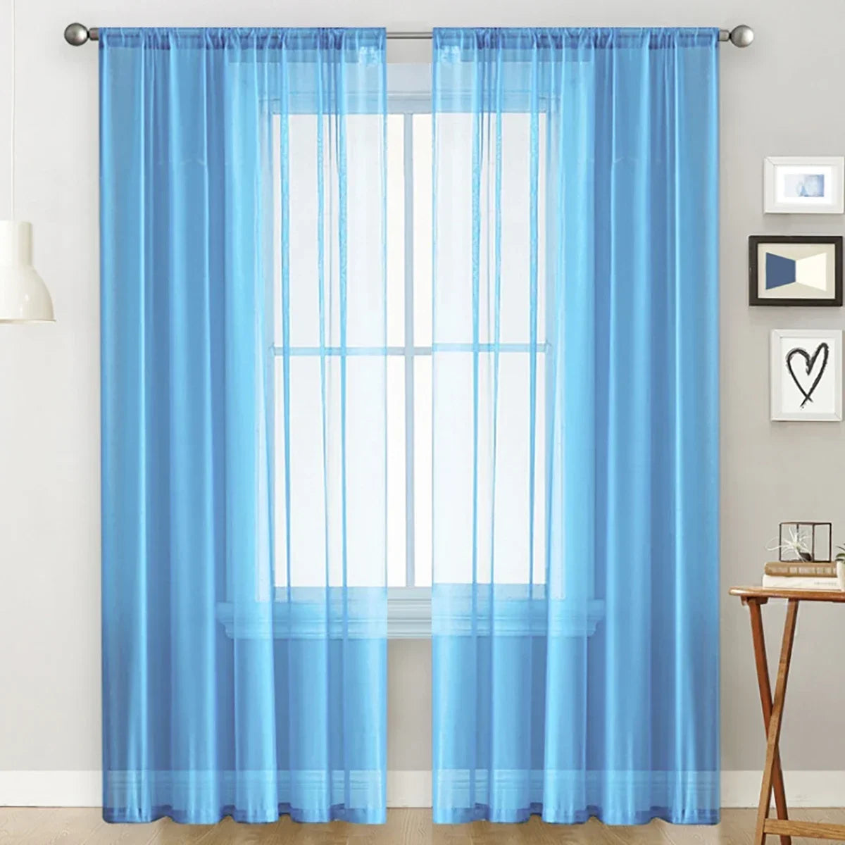 Light blue sheer curtain panels hanging over a window in a living room or bedroom.