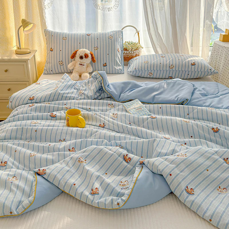 Light blue striped quilt with a cartoon pattern featuring small animals on a bed.