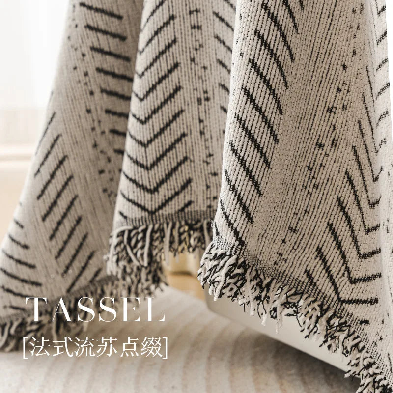 Close-up of a beige and black chevron patterned tasseled sofa cover fabric.