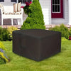 A dark gray waterproof fire pit cover with a drawstring lying on a green lawn in front of a house.