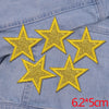 Five gold glitter star patches sewn onto a denim fabric.