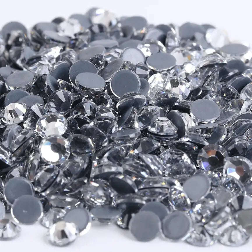 A pile of clear and black crystal AB flatback rhinestones for crafts and decor.
