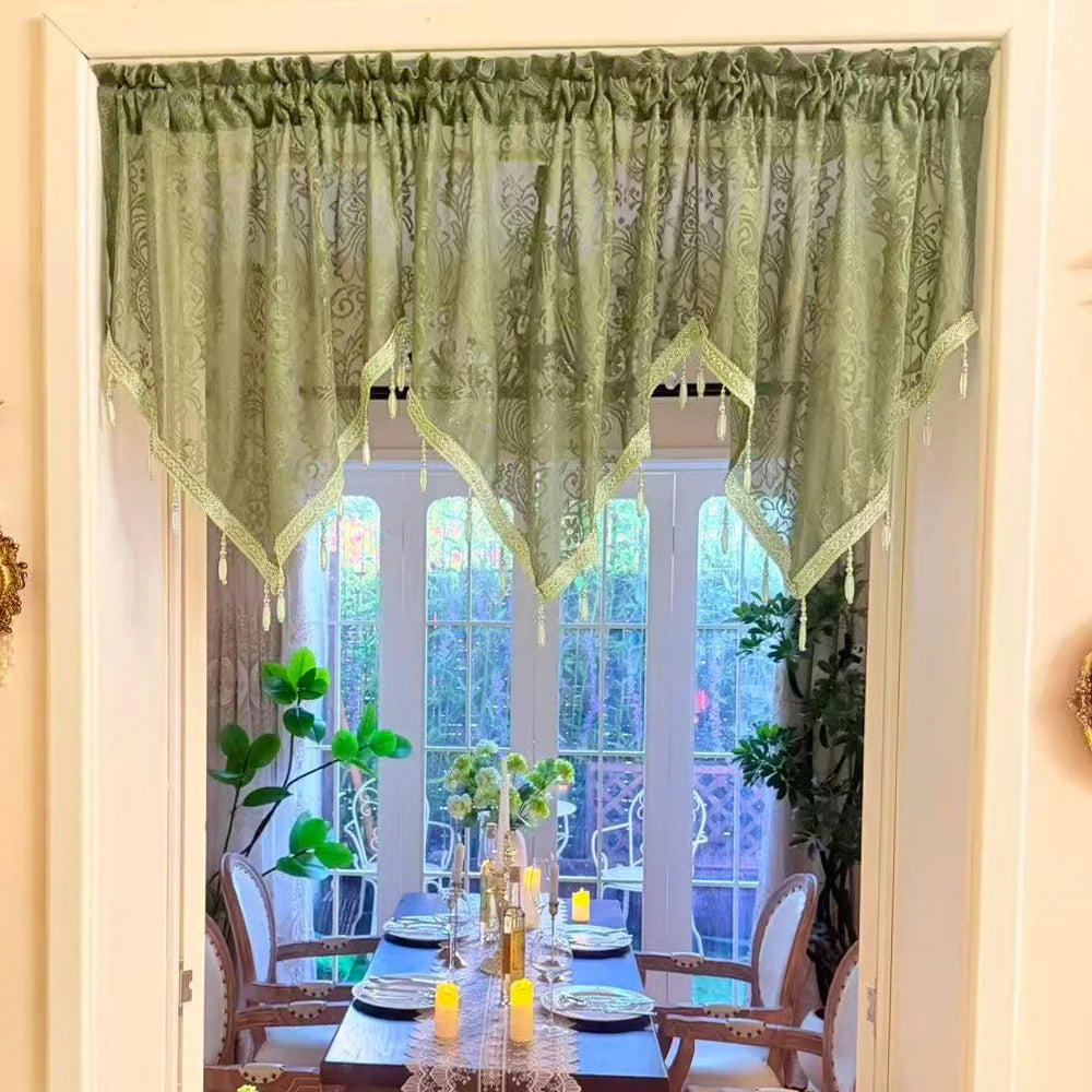 Elegant black lace curtain valance framing a window with green sheer fabric and wooden furniture
