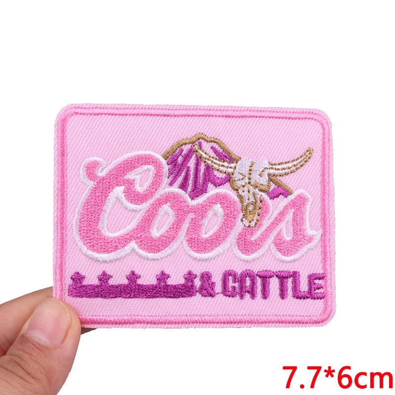 Pink embroidered patch with the text Cools & Cattle in pink and gold thread