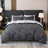 A set of three gray pattern print duvet covers and pillowcases displayed on a bed.